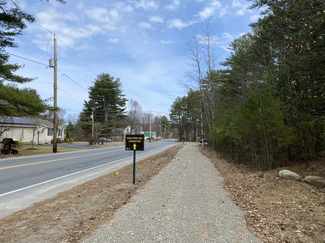 A picture of a gravel trail with a sign saying Rush Pond Connector.